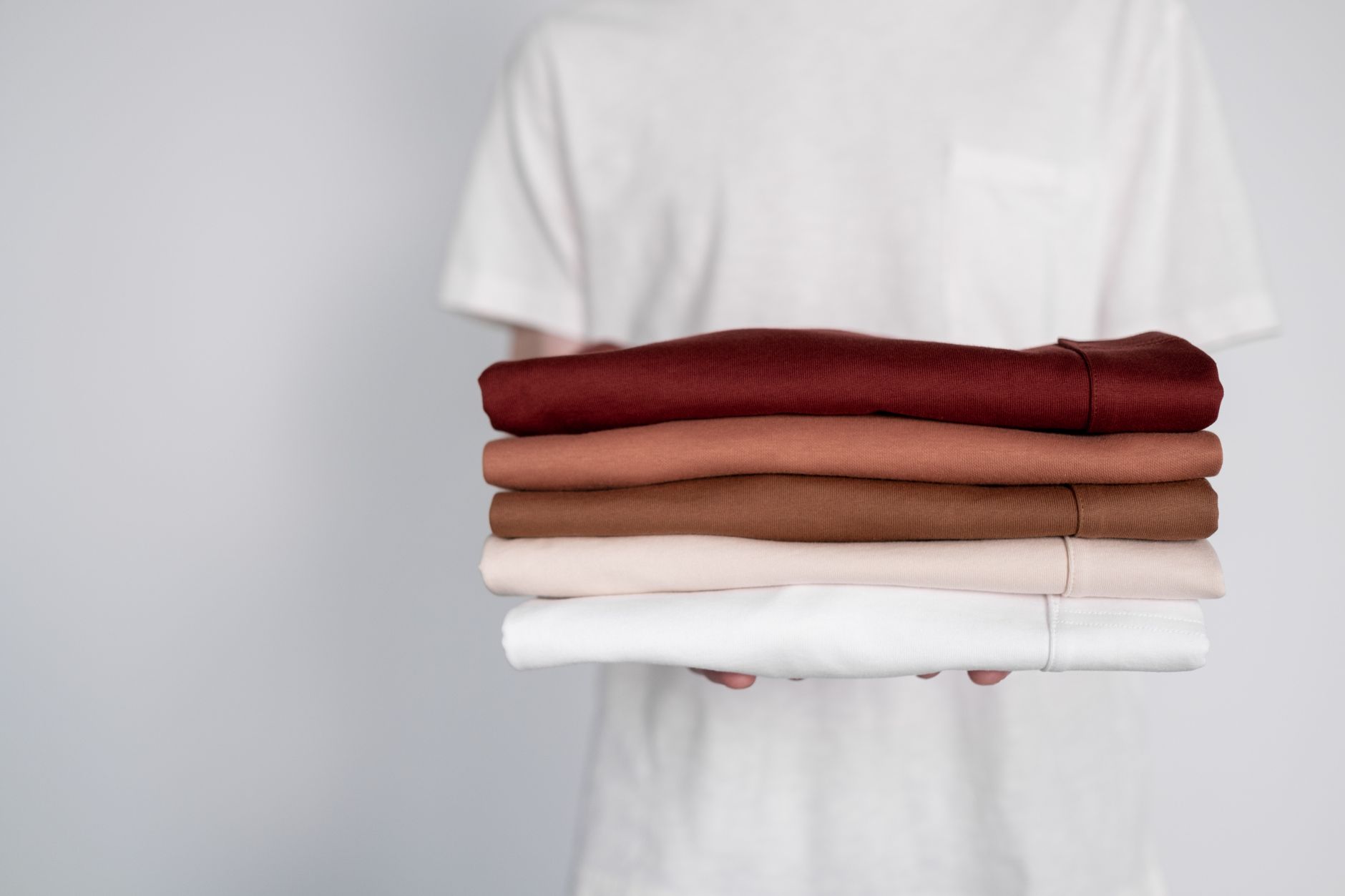 たたんだ服を重ねて持つ手元